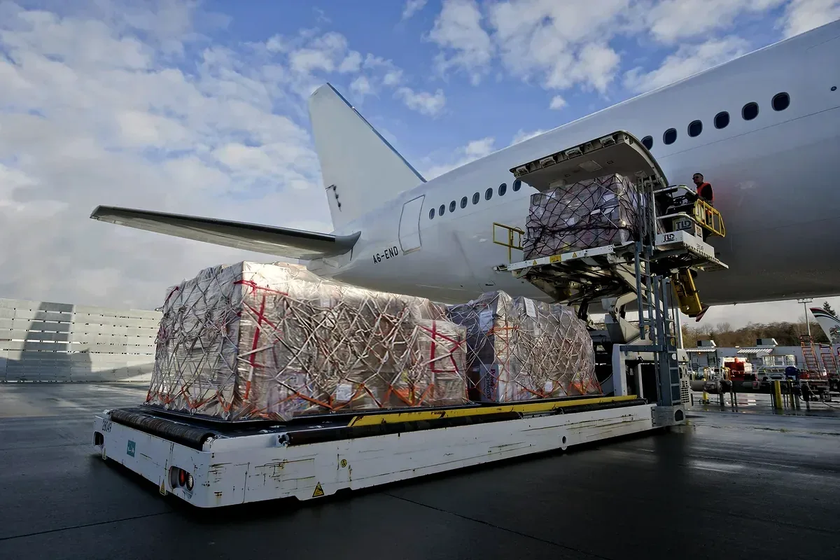 A wrapped cargo pallet being raised into an aircraft hold on the apron